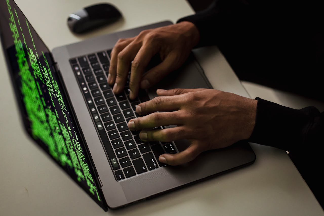 Services From above of crop anonymous male hacker typing on netbook with data on screen while sitting at desk