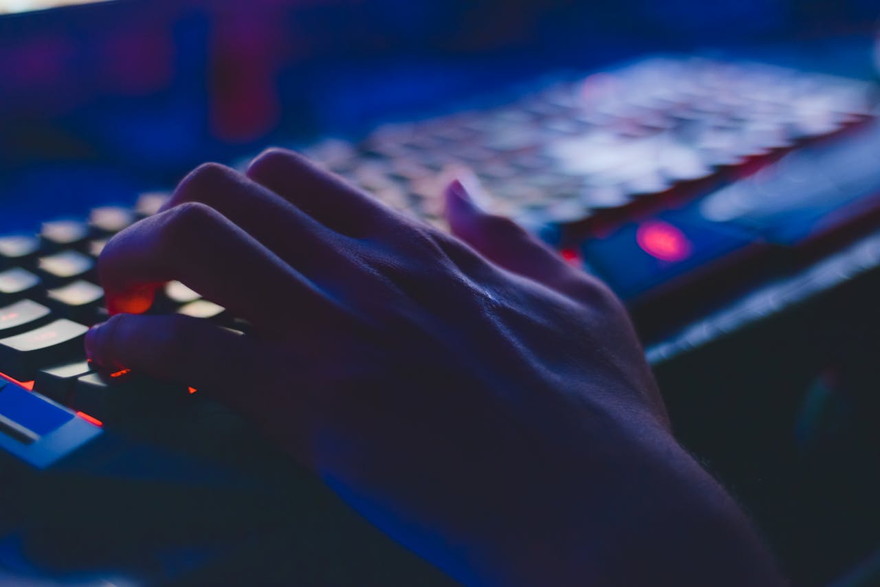 Services A hand typing on a glowing keyboard in dim lighting, perfect for tech themes.